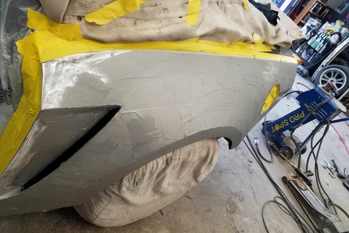 A rear bumper masked and in primer, ready for color